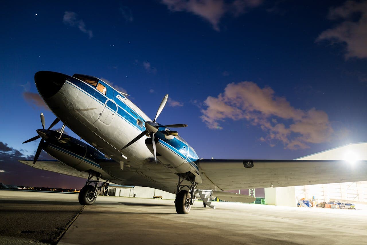 Polished twin-propeller aircraft parked on the apron at dusk